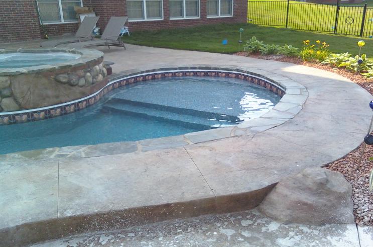 swimming pool with sunshelf and sun-shelf has bluestone coping and spill over spa located in northville, mi